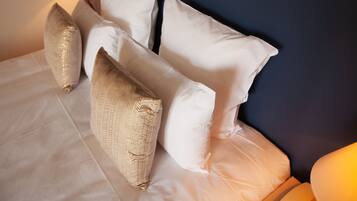 Un letto rifatto con lenzuola bianche e diversi cuscini decorativi.