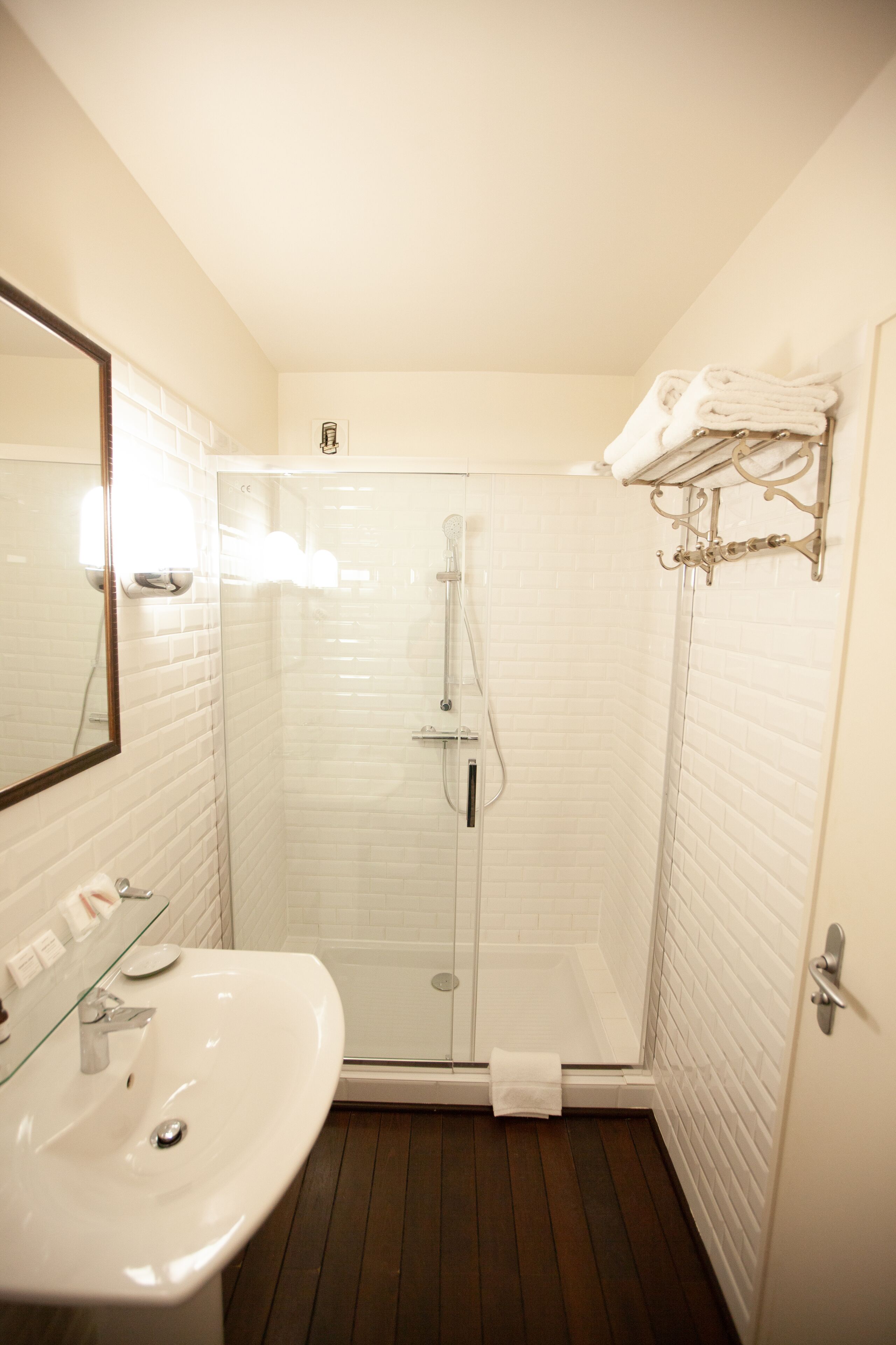 A bathroom with a white sink, a glass-enclosed shower, and a towel rack.