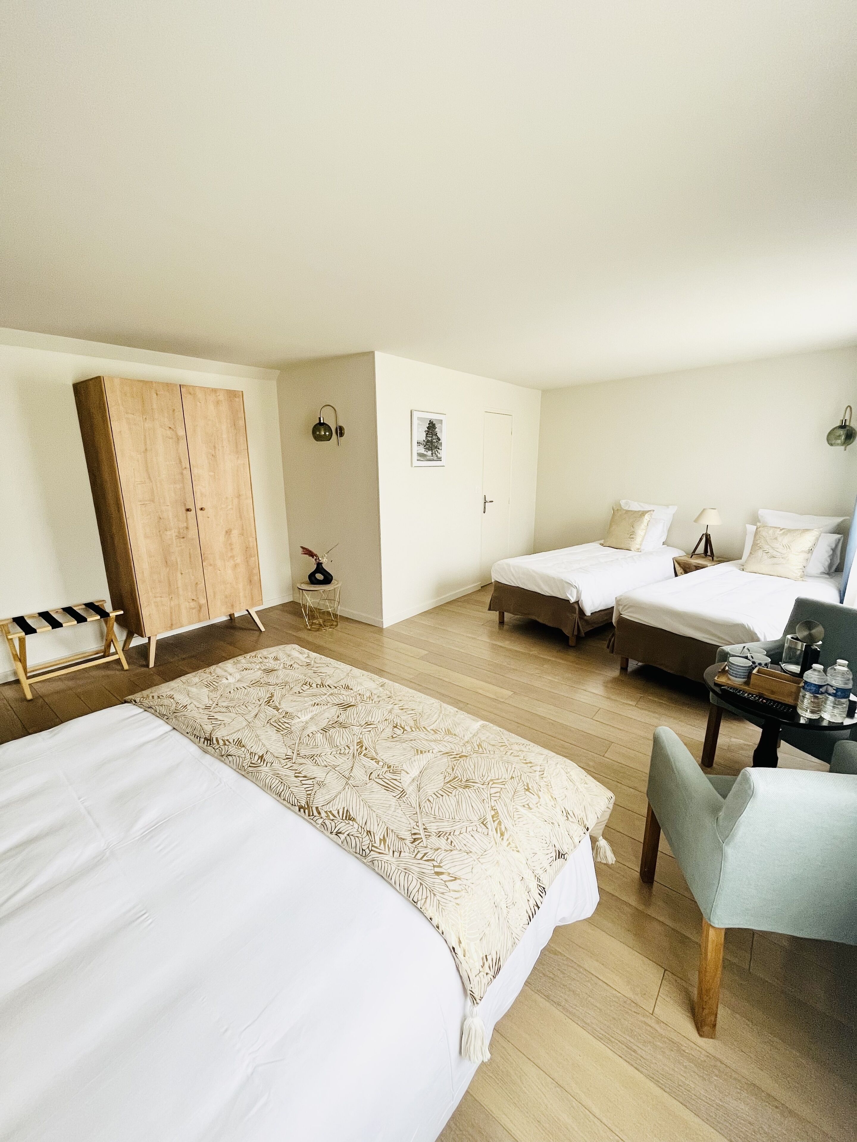 A bedroom with two beds, a wooden wardrobe, a small table with a chair, and a decorative rug.