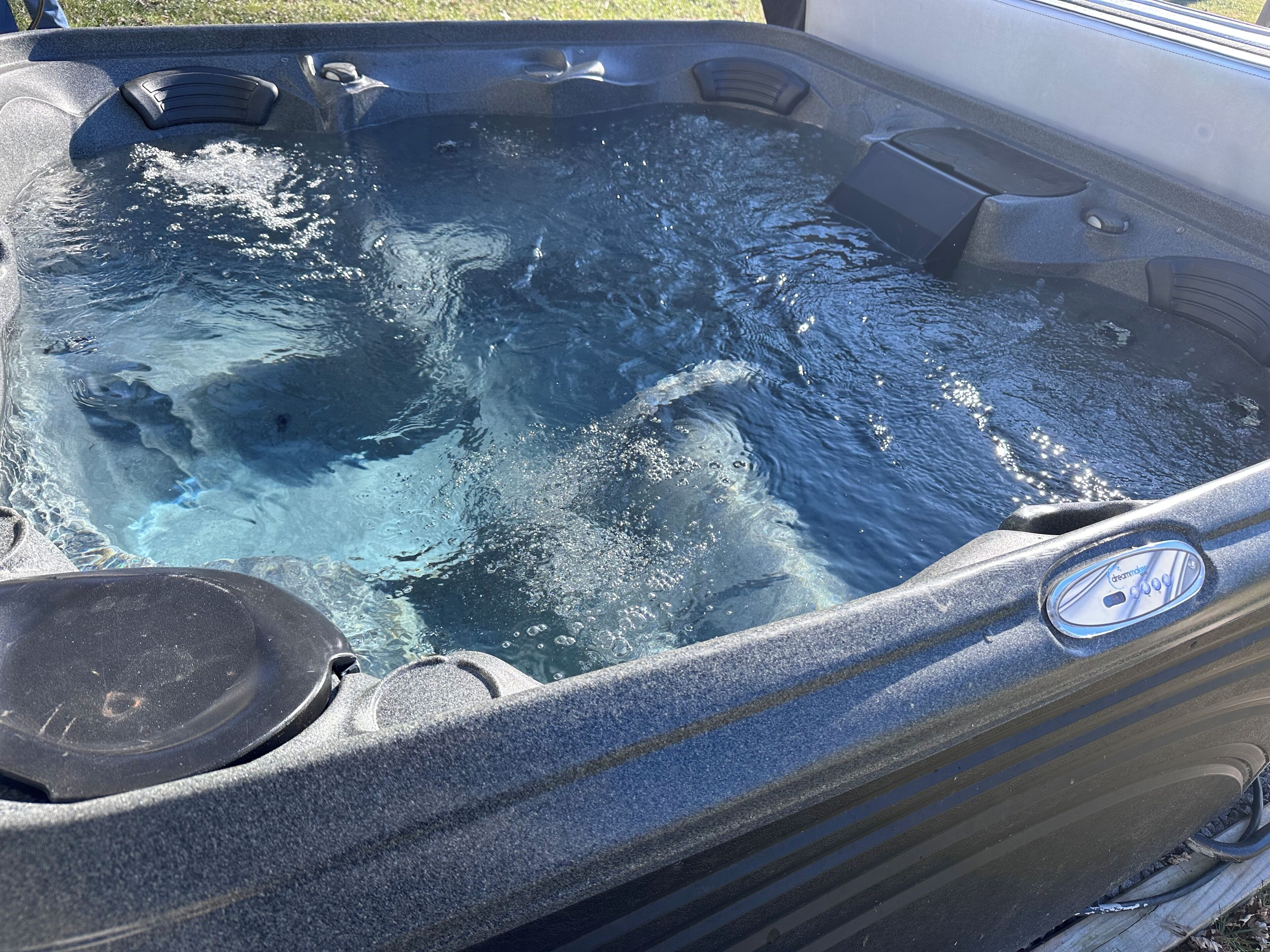 A hot tub with a visible brand logo, a control panel, and a water pump.