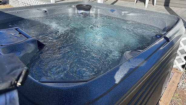 A hot tub with a built-in heater, surrounded by a wooden deck and outdoor furniture.