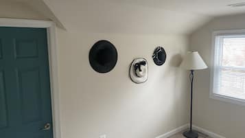Una habitación con una puerta verde azulado, una lámpara de pared y tres sombreros colgados en la pared.