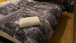 A bedroom with a cityscape mural, a bed with a patterned bedspread, and a modern ceiling light fixture. - Chez Bebel with panoramic pool (Casablanca)