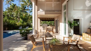 Eine überdachte Terrasse im Freien mit Pool, Liegestühlen und Grillplatz.