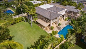 Ein Wohnhaus mit Swimmingpool, überdachter Terrasse und üppiger tropischer Bepflanzung.