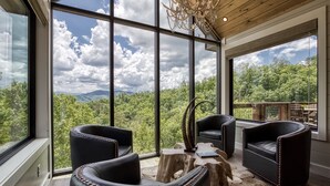 A modern interior with large windows offering a view of a forested landscape. - Summit Trails Mansion - Luxury Cabin with Views! (Sevierville)