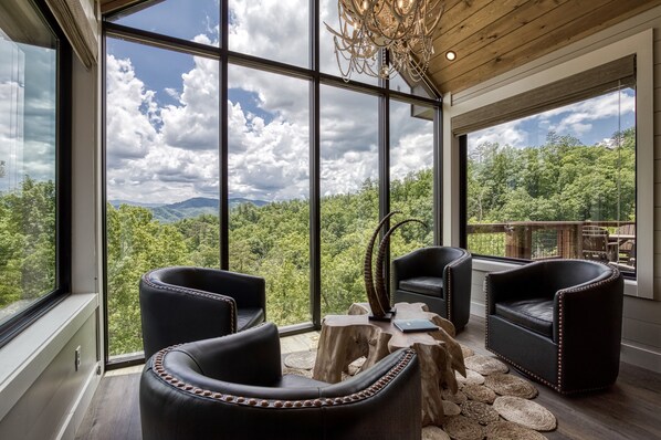 A modern interior with large windows offering a view of a forested landscape.