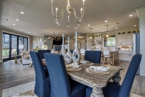 A spacious dining area with a large table set for six, surrounded by blue upholstered chairs.
