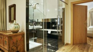 A modern bathroom with a glass shower enclosure, a wooden dresser, and a mirror on the wall.