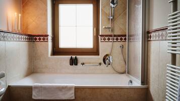 Un baño con bañera, ventana y ducha.