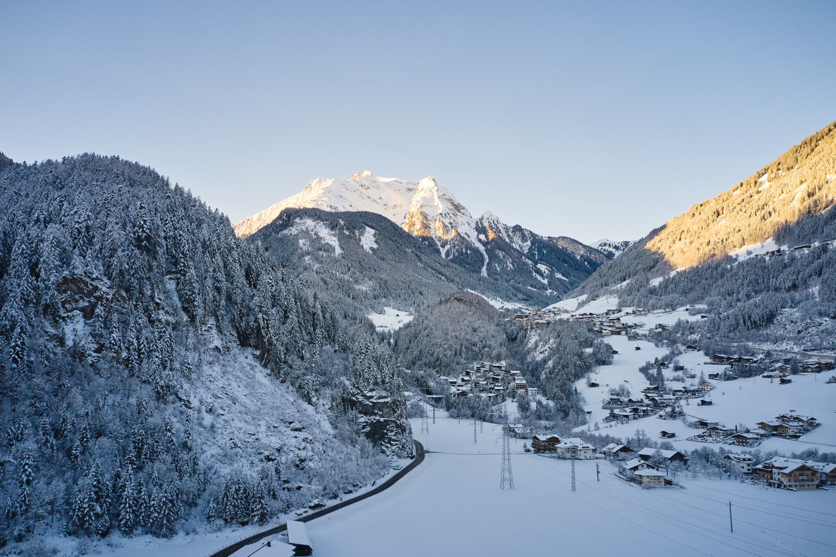Un village de montagne enneigé, sous un ciel dégagé.