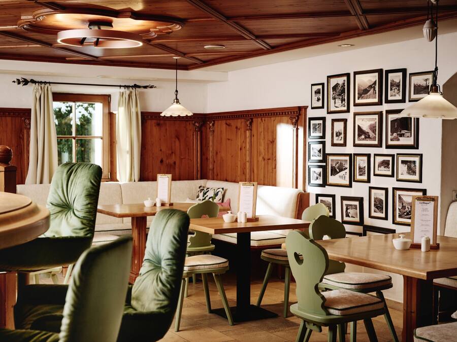 A dining area with wooden tables and chairs, a wooden ceiling, and framed pictures on the wall.
