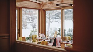 Un comedor acogedor con paredes de madera y ventanas amplias, que ofrece vistas a un paisaje nevado.