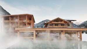 Una cabaña de madera con un jacuzzi cubierto de vidrio, frente a un paisaje montañoso.