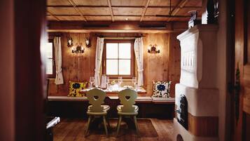 Un intérieur en bois avec une table à manger dressée pour deux personnes, un banc et une cheminée.