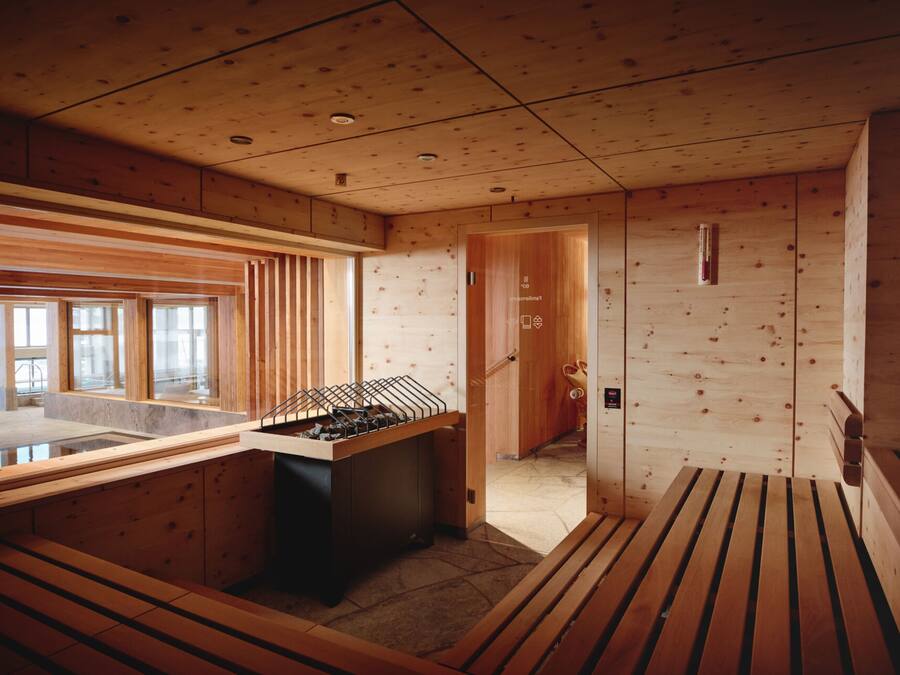 A wooden interior with a foosball table, a bench, and a door leading to another room.