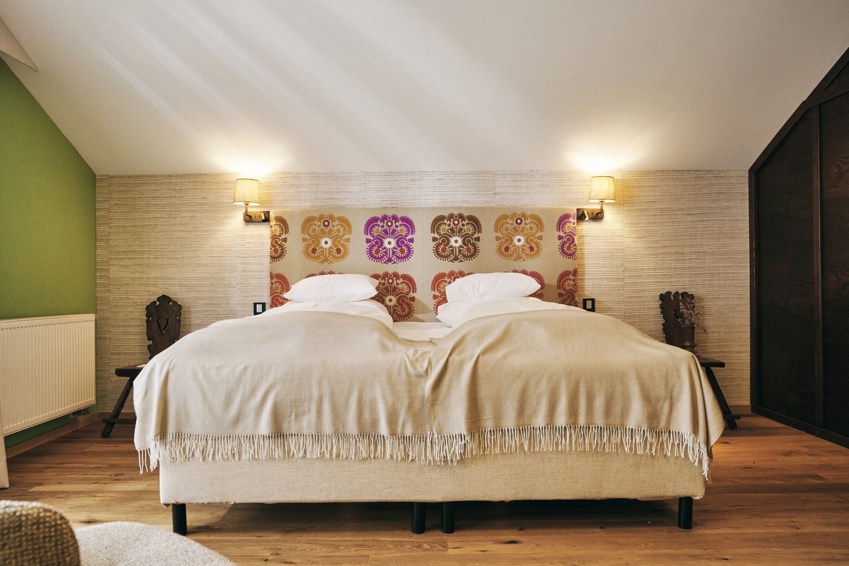 Un dormitorio amplio con una cama grande, dos mesitas de noche y un cabecero decorativo.
