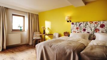 A hotel room with a bed, a desk, a chair, a lamp, and a window with curtains.