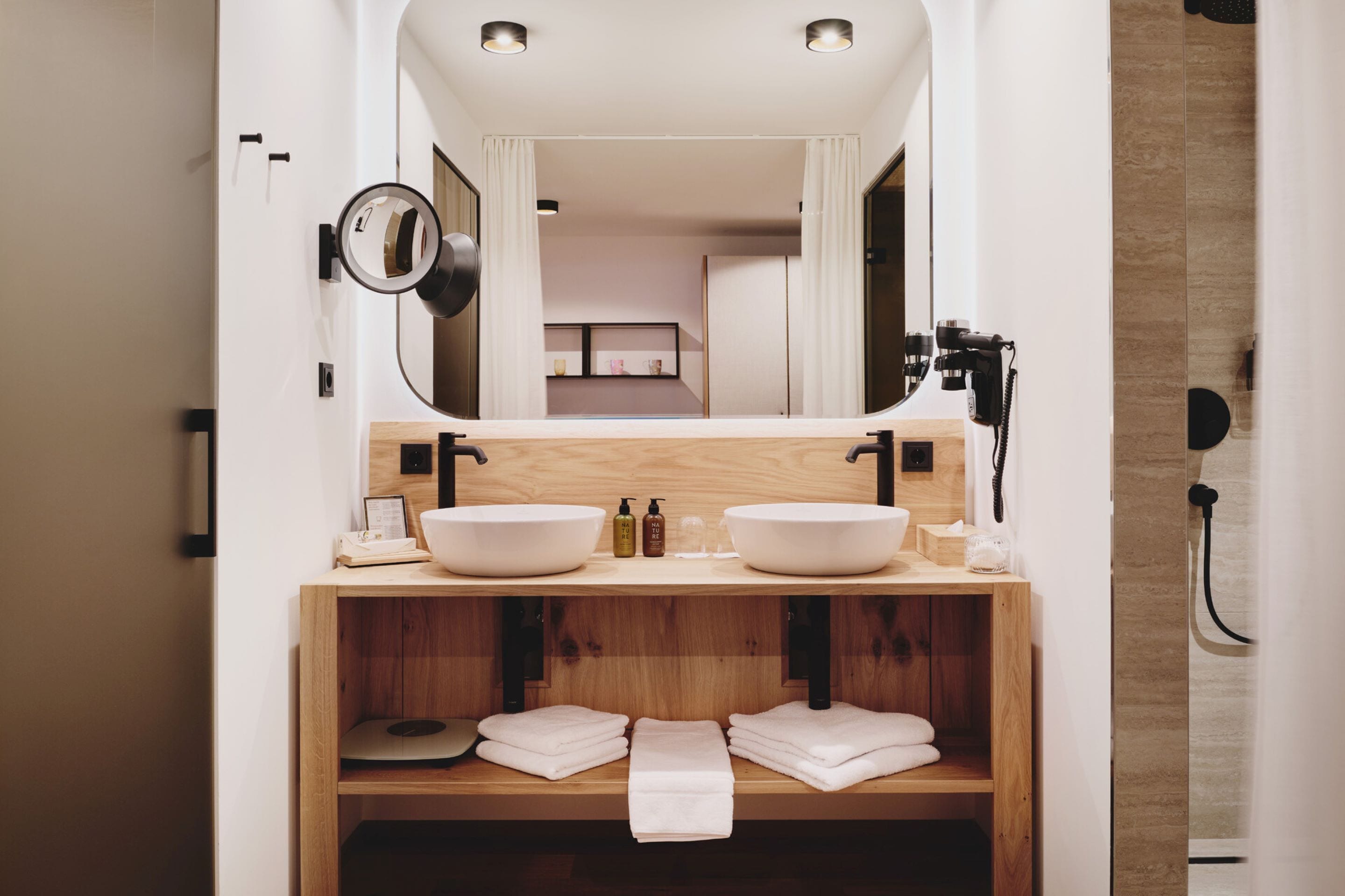Un baño moderno con lavamanos doble, tocador de madera y un espejo grande.