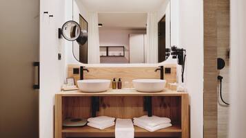 Un baño moderno con lavamanos doble, tocador de madera y un espejo grande.