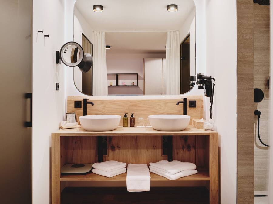 Un baño moderno con lavamanos doble, tocador de madera y un espejo grande.