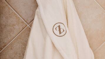 A white robe with a logo hanging on a tiled wall.