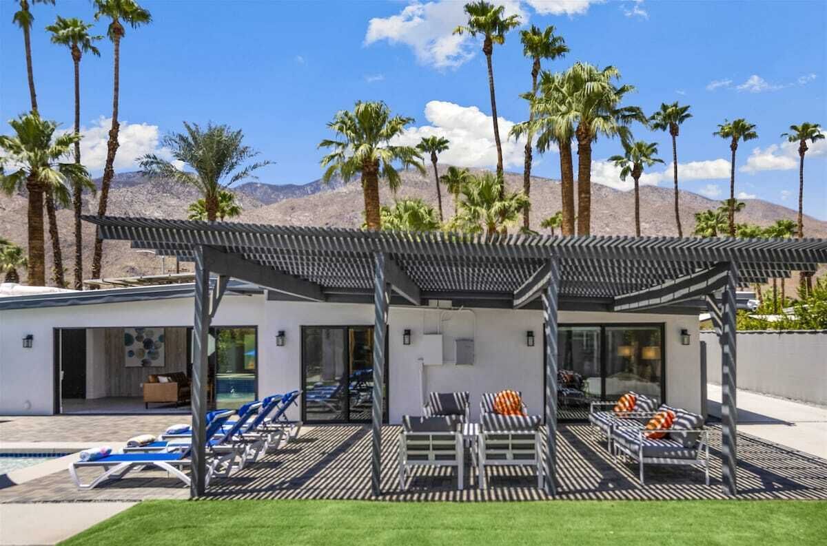 Une maison moderne dotée d’une piscine, d’un espace salon extérieur et de palmiers.