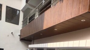 Un patio con piso estampado, un balcón de madera y una puerta de cristal que da al interior.