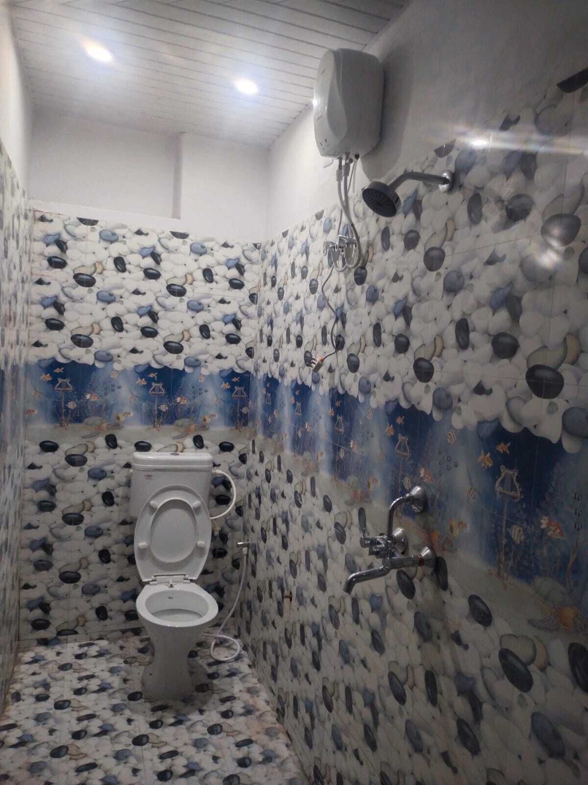 Een badkamer met toilet, douche en een muur versierd met een patroon van stenen en vissen.