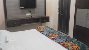 Un dormitorio con cama, televisor montado en la pared, armario y aire acondicionado.