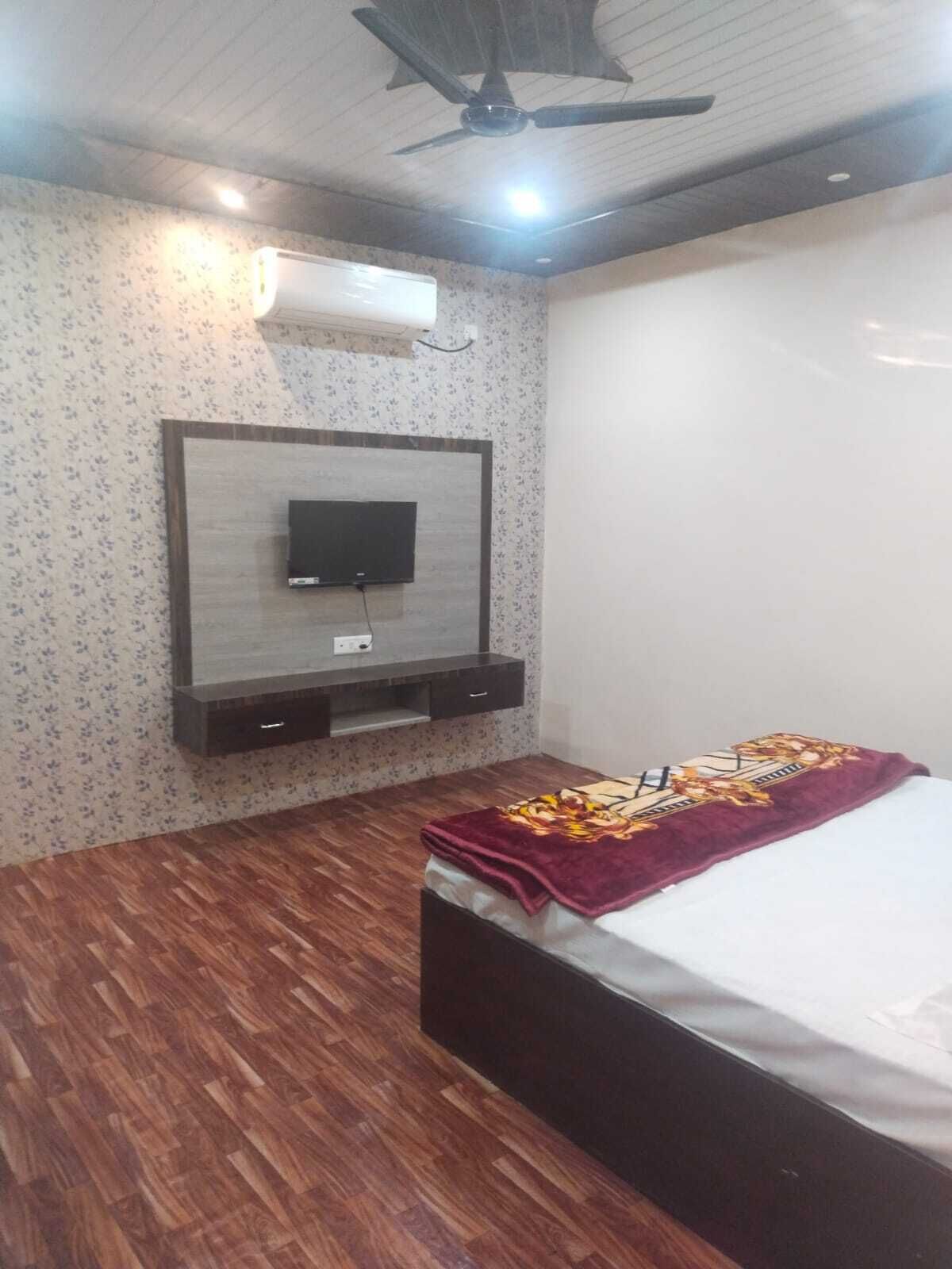 A bedroom with a bed, a TV mounted on the wall, and a ceiling fan.