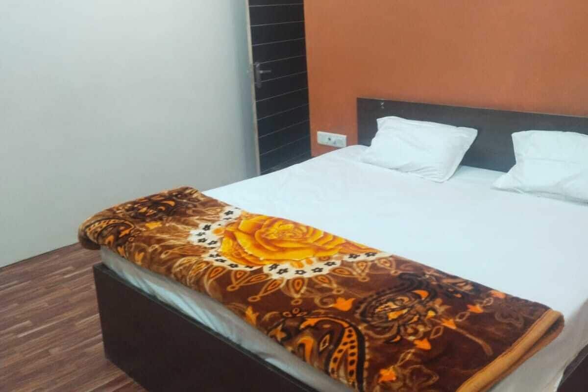 Una habitación de hotel con cama, suelo de madera y pared marrón.