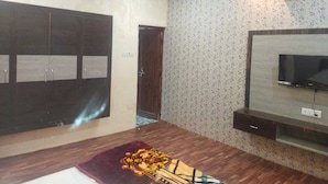 Una habitación con un armario de madera oscura, un televisor sobre un mueble de madera y un papel tapiz estampado.