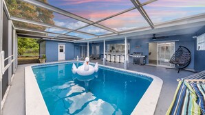 A swimming pool with a swan float, a ceiling fan, and a hammock.