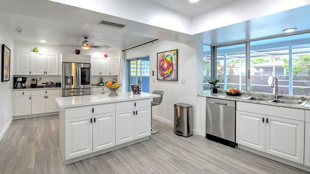 A modern kitchen with white cabinetry, stainless steel appliances, and a large island.