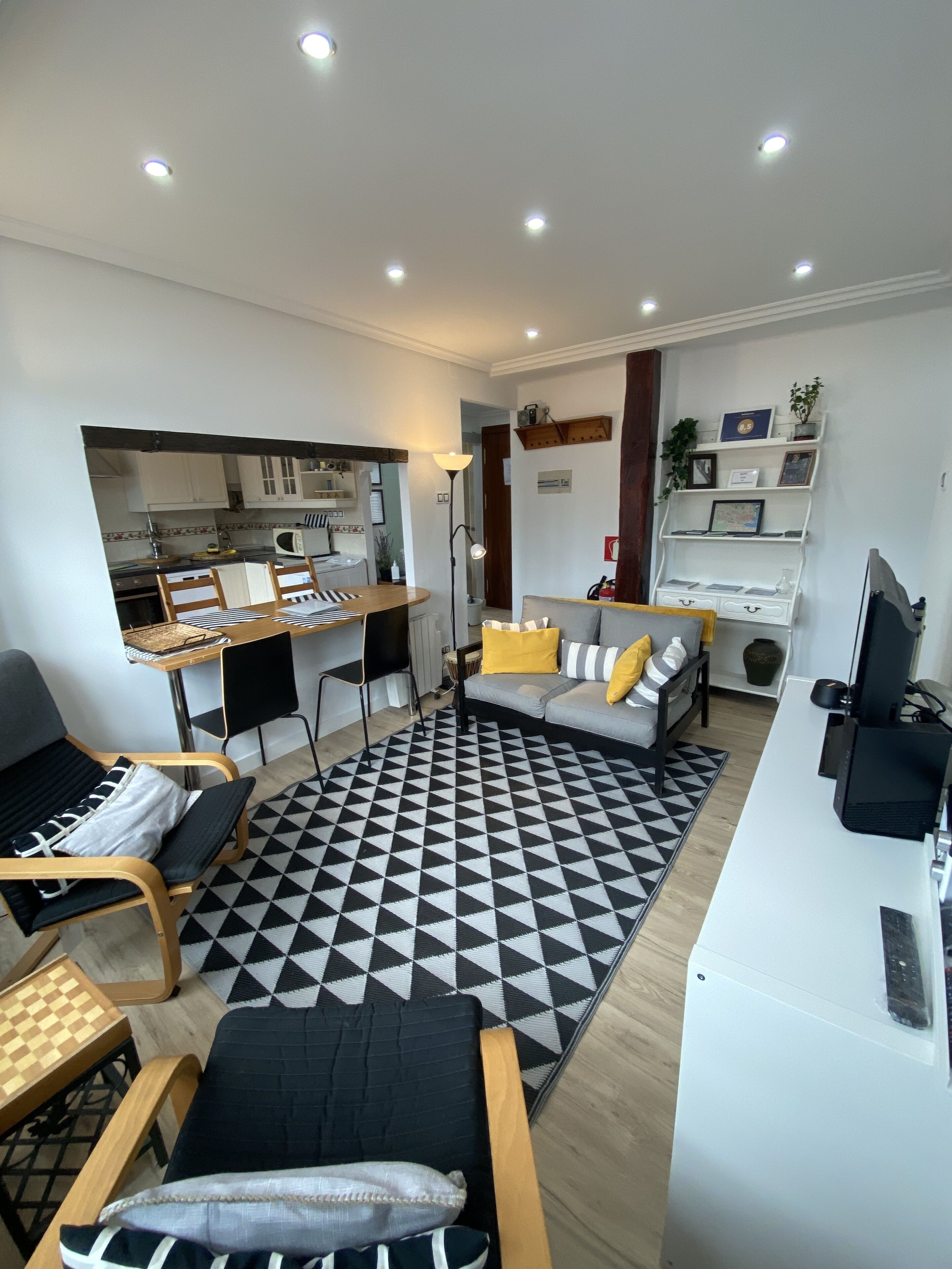 Una sala moderna con sofá, mesa de comedor y zona de cocina.