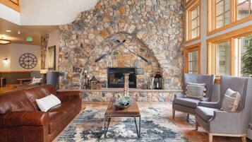 Un salón acogedor con chimenea de piedra, sofá de cuero y sillones.