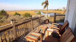 Een houten terras met tuinmeubilair, uitzicht op een rivier en een palmboom.