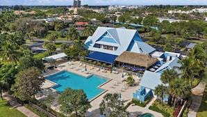 A resort with a large pool, outdoor seating, and a thatched-roof structure. - POSHPADZ -OceanView Villa-Resort Complex, Penthouse, Sleeps 4, Walk to Beach (Jupiter)