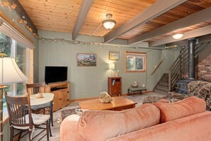 Un salon chaleureux avec une télévision, des meubles en bois, une cheminée et un escalier.
