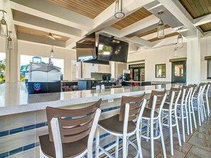A modern kitchen with a large island, bar seating, and a flat-screen TV.