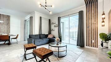 Uma sala de estar moderna com sofá seccional, mesa de centro e área de jantar com cadeiras.