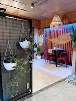 Un comedor con plantas colgantes, una mesa y sillas rojas.