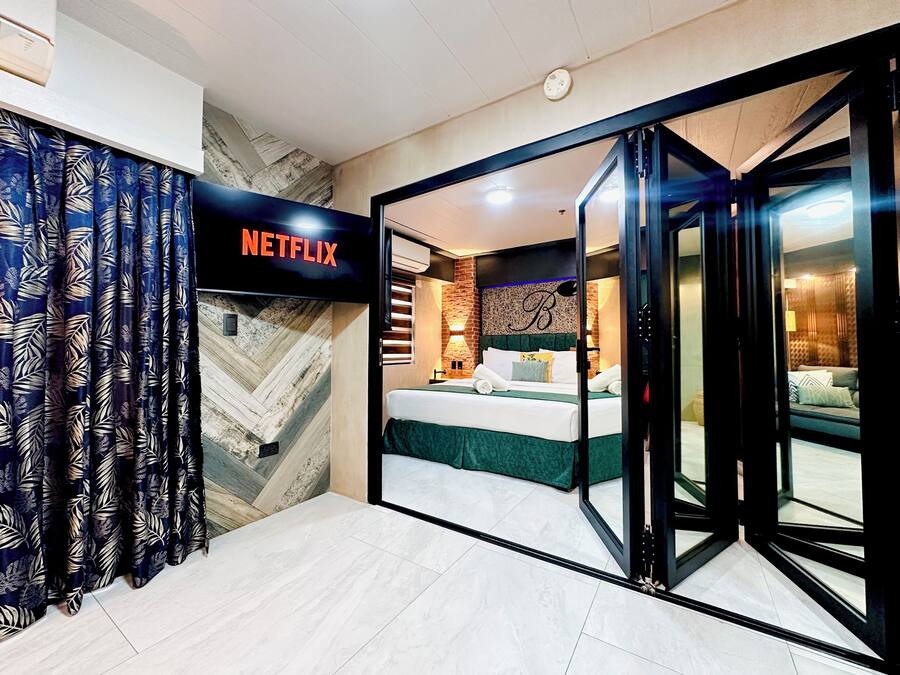 Une chambre d’hôtel avec un lit, une porte coulissante donnant sur un balcon et un panneau indiquant la présence d’un service Netflix.