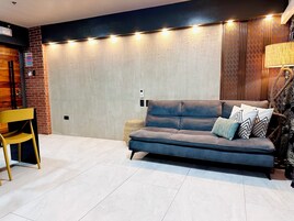 A modern living room with a sofa, a chair, a lamp, and a patterned wall.