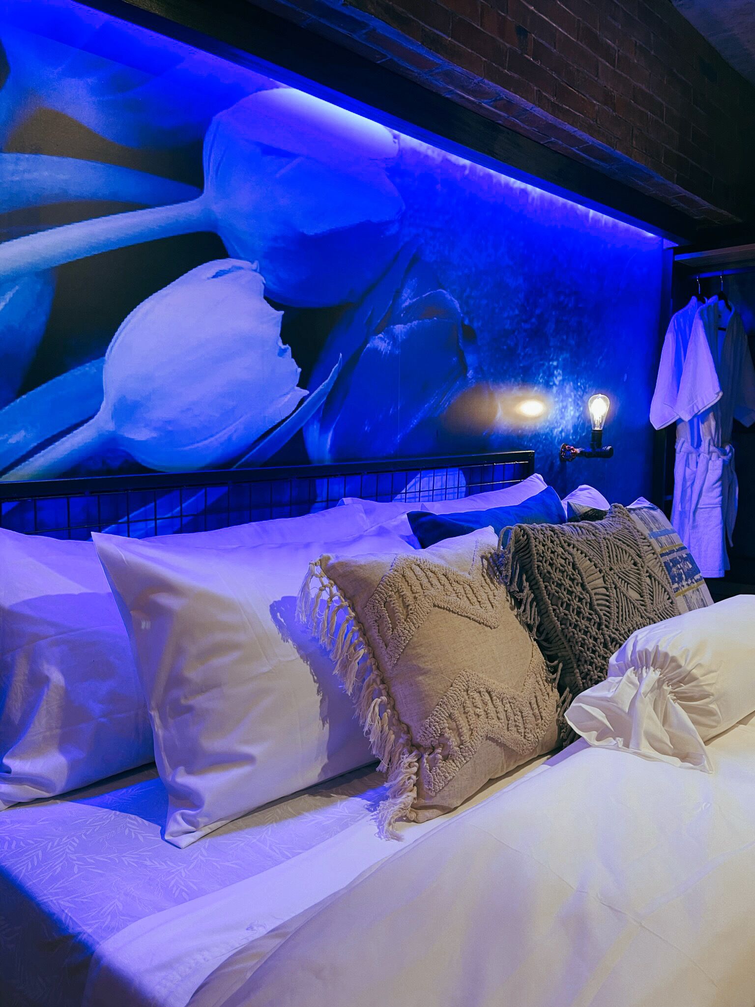 Une chambre d’hôtel avec un grand lit, une fresque murale et un luminaire.