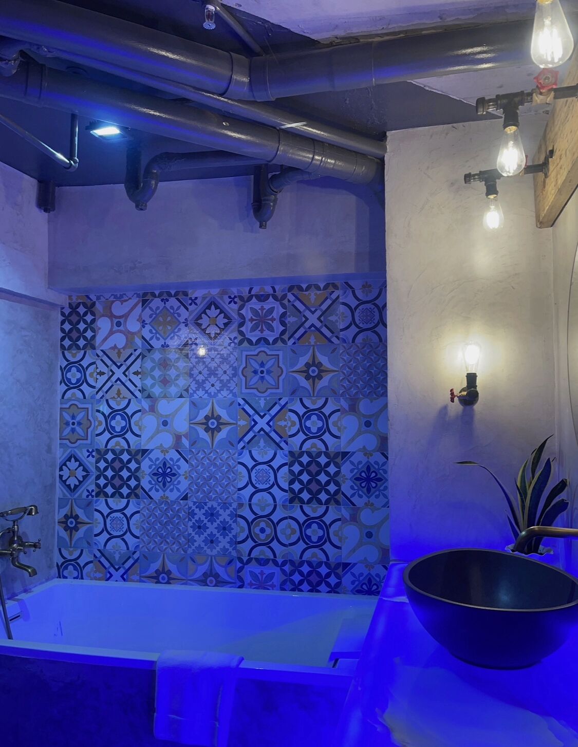 Un baño con pared de azulejos, un lavamanos y un lavabo.
