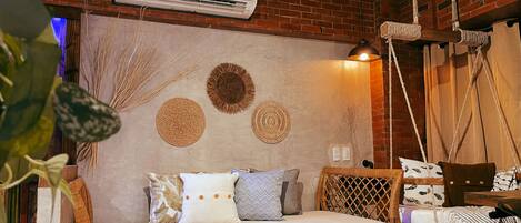 A cozy room with a wicker sofa, a hanging swing, and a wall decorated with woven circles.