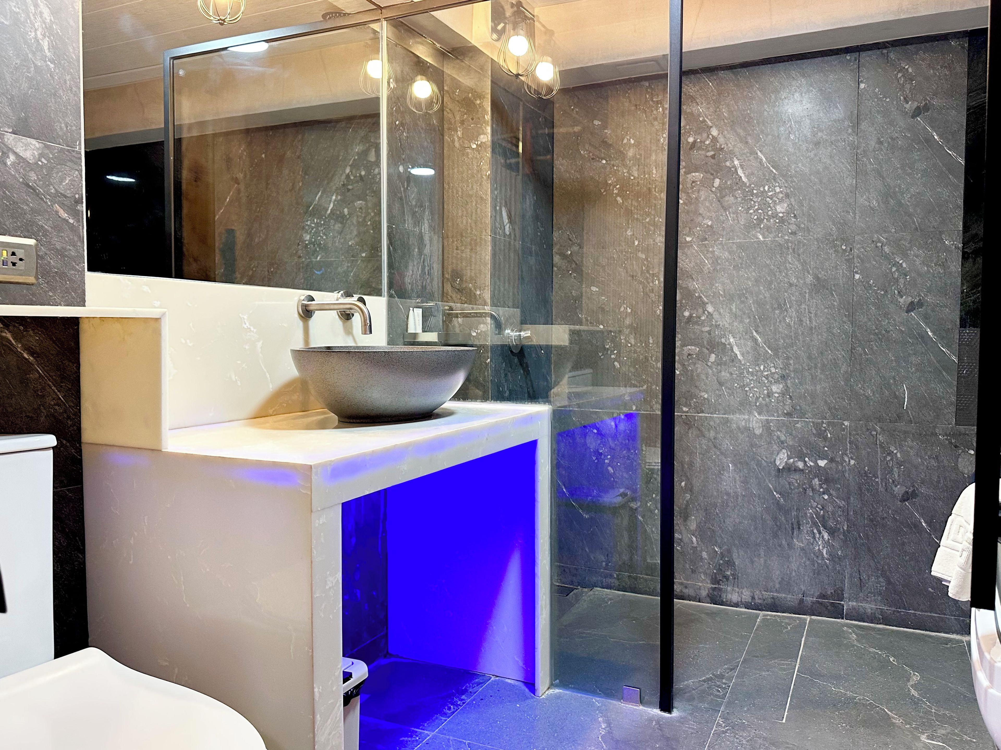 A modern bathroom with a large mirror, a vessel sink, and a glass-enclosed shower area.