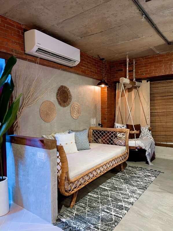 A cozy room with a wicker sofa, a hanging swing, and a large air conditioning unit mounted on the wall. - Blue Tulip (Lapu-Lapu)
